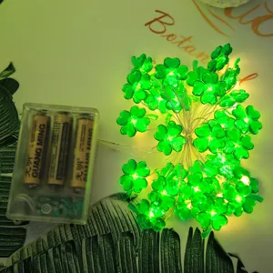 Close-up detail of glowing green four-leaf clover LED string light battery box setup.