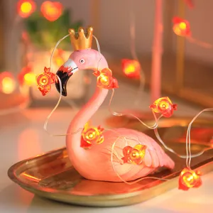 Charmant roze flamingobeeldje met gouden kroon en knipperende LED-hartjeslichtketting.