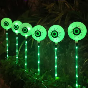 Detalle de estaca solar LED Halloween globo ocular con luz verde para decoración jardín.