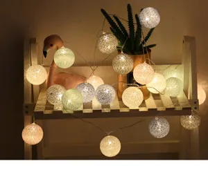 Detailaufnahme gemütlicher LED-Baumwollball-Lichterkette auf einem Holzregal für Zimmerdeko.