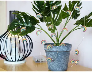 Primer plano de luces LED de cadena de arcoíris coloridas decoradas en hojas de plantas.