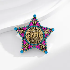 Close-up of a vintage sheriff star brooch with blue and pink rhinestones and carved text.