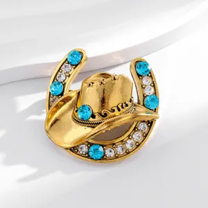 Vintage gold-tone horseshoe and cowboy hat brooch detailed with sparkling blue and clear rhinestones.