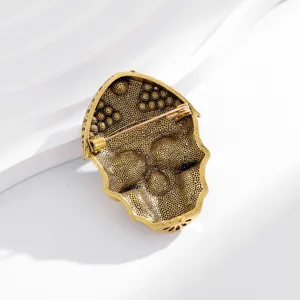 Close-up detail shot of the reverse side of a vintage gold-tone retro skull brooch accessory.