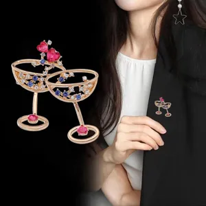 Broche dorado de doble copa de cóctel elegante con cristales brillantes y piedras rojas.