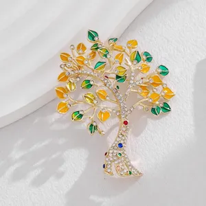 Gros plan d'une broche arbre doree avec des feuilles emaillees colorees et des pierres scintillantes.