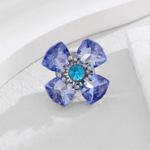 Detailopname van een sprankelende kristallen bloembroche met blauwe facetblaadjes en magneetsluiting.