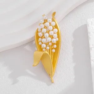 Exquisite pearl lily of the valley brooch detail, elegant gold metal leaf lapel pin design.