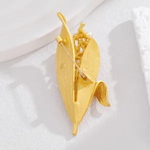 Detailaufnahme einer Perlen Blatt Brosche, goldener Metall Modeschmuck Anstecknadel.