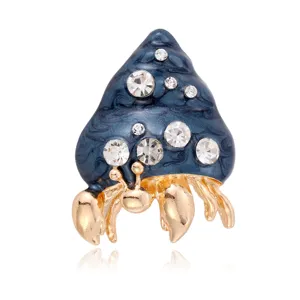 Detailed closeup of exquisite hermit crab shell brooch with blue enamel and sparkling rhinestones.