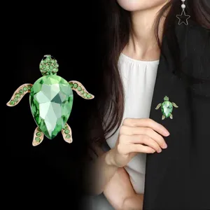 Close-up detail of the sparkling green crystal sea turtle brooch, elegant rhinestone pin accessory.