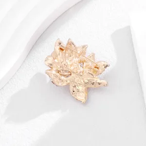 Close-up detail shot of the gold-toned flower brooch back showing secure pin structure.