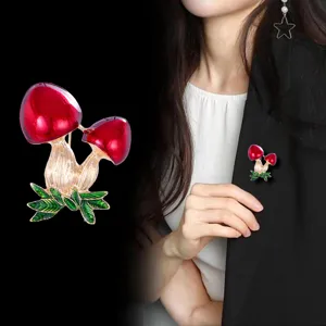 Squisita spilla smaltata a fungo rosso, primo piano ed effetto indossato per look alla moda.