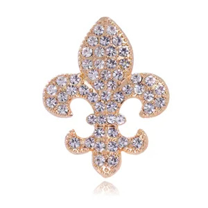 Close-up detail of a stunning gold crystal rhinestone fleur-de-lis brooch accessory.
