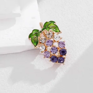 Exquisite detail view of the sparkling grape brooch featuring green enamel leaves and crystals.