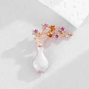 Elegant vintage white vase and flower brooch with sparkling crystals and gold tone finish.