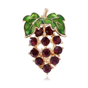 Detailed view of the sparkling red rhinestone grape brooch with green enamel leaves, gold tone.