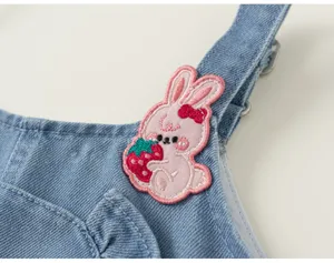 Détail de patch lapin rose et fraise brodé mignon sur robe chasuble en jean d'été fille.