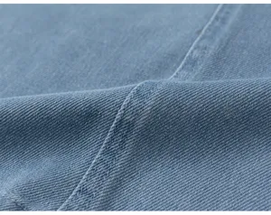 Vue détaillée d'un tissu en denim bleu résistant avec des coutures soignées et de haute qualité.
