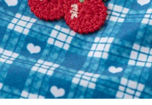 Detailed view of girls blue plaid swimsuit fabric featuring heart print and crochet cherry decor.