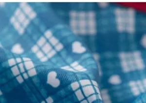 Close-up detail of blue plaid fabric with cute white hearts pattern for kids swimwear text