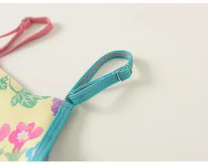 Children swimsuit detail close-up showing floral print yellow fabric and blue straps.