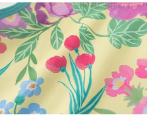 Detailed view of girl's floral print swimsuit fabric with vibrant yellow background.
