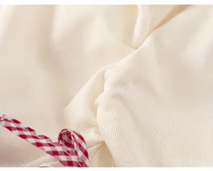 Close-up view of soft ribbed cotton fabric with red and white checkered ribbon bow detail.