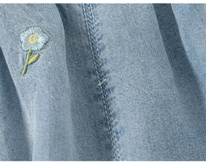 Dettaglio di pantaloni in denim per neonati con deliziosa ricamo floreale e cuciture curate.
