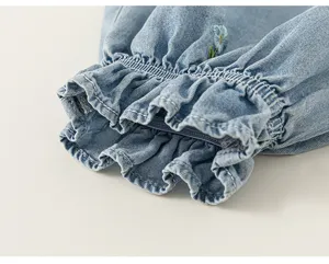 Dettaglio jeans bambina, orlo azzurro con grazioso ricamo floreale ed elastici arricciati.