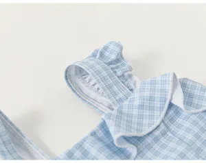 Close-up detail of girls blue plaid one-piece swimsuit featuring cute ruffles and delicate trim.