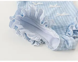 Girls blue plaid swimsuit detail close-up showcasing delicate ruffles and cute white bows.