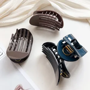 Detailed view of matte oval hair claw clips with strong metal spring in dark tones.
