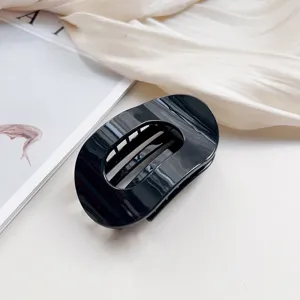 Detailed close-up of a stylish black oval hair claw clip, perfect for elegant buns and updos.