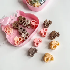 Gros plan détaillé de petites pinces à cheveux colorées en nœud dans une boîte rose.