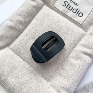 Close-up detail of a matte black mini hair claw clip featuring a sleek flat oval hollow design.