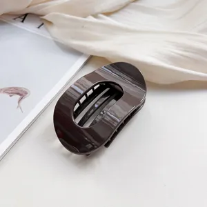 Close-up detail of the dark brown oval hair claw clip, minimalist design for daily elegant updos.