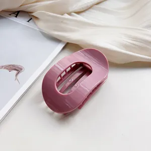 Close-up detail of the elegant pink oval hair claw clip, featuring a smooth silicone texture.