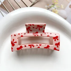 Pink square hair claw clip featuring cute red bow and heart patterns for sweet daily styling.