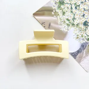 Close-up detail of the minimalist yellow matte square hair claw, showing smooth texture.