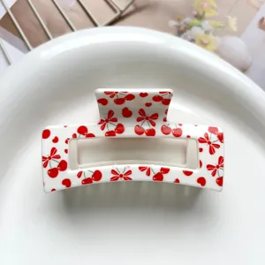 Close-up of square hair claw clip with sweet red cherry and bow print design for women hair.