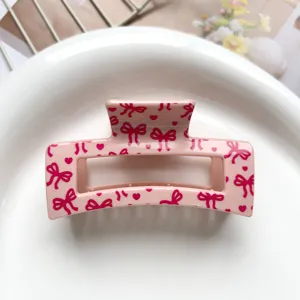 Close-up detail of a pink hair claw clip featuring cute dark pink bows and sweet heart prints.