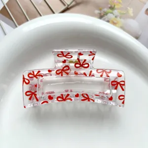 Detailed view of square transparent hair claw clip with sweet red bows and hearts print.