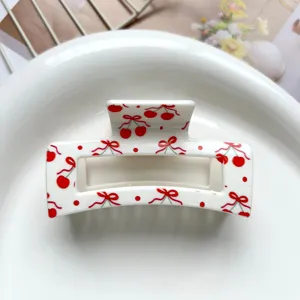 Detailed shot of a white square hair claw clip featuring sweet red cherry and bow print.