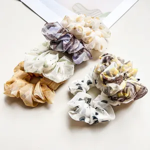Close-up detail of chic chiffon hair scrunchies with rhinestones and sweet patterns.