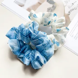 Close-up detail of stylish chiffon hair scrunchies with sparkling rhinestones and chic patterns.