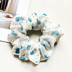 Close-up detail of white chiffon hair scrunchie featuring blue hearts and shimmering rhinestones.