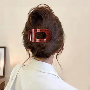 Detail view of large flat hair claw clip, translucent amber oval hollow design for women styling.