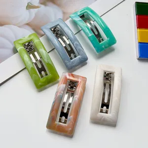 Detail view of marble resin hair clips featuring rectangular cutout design and metal barrettes.