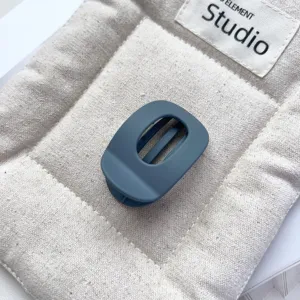 Matte dark blue oval hollow hair claw clip, detail view of compact mini shark clip for half up do.